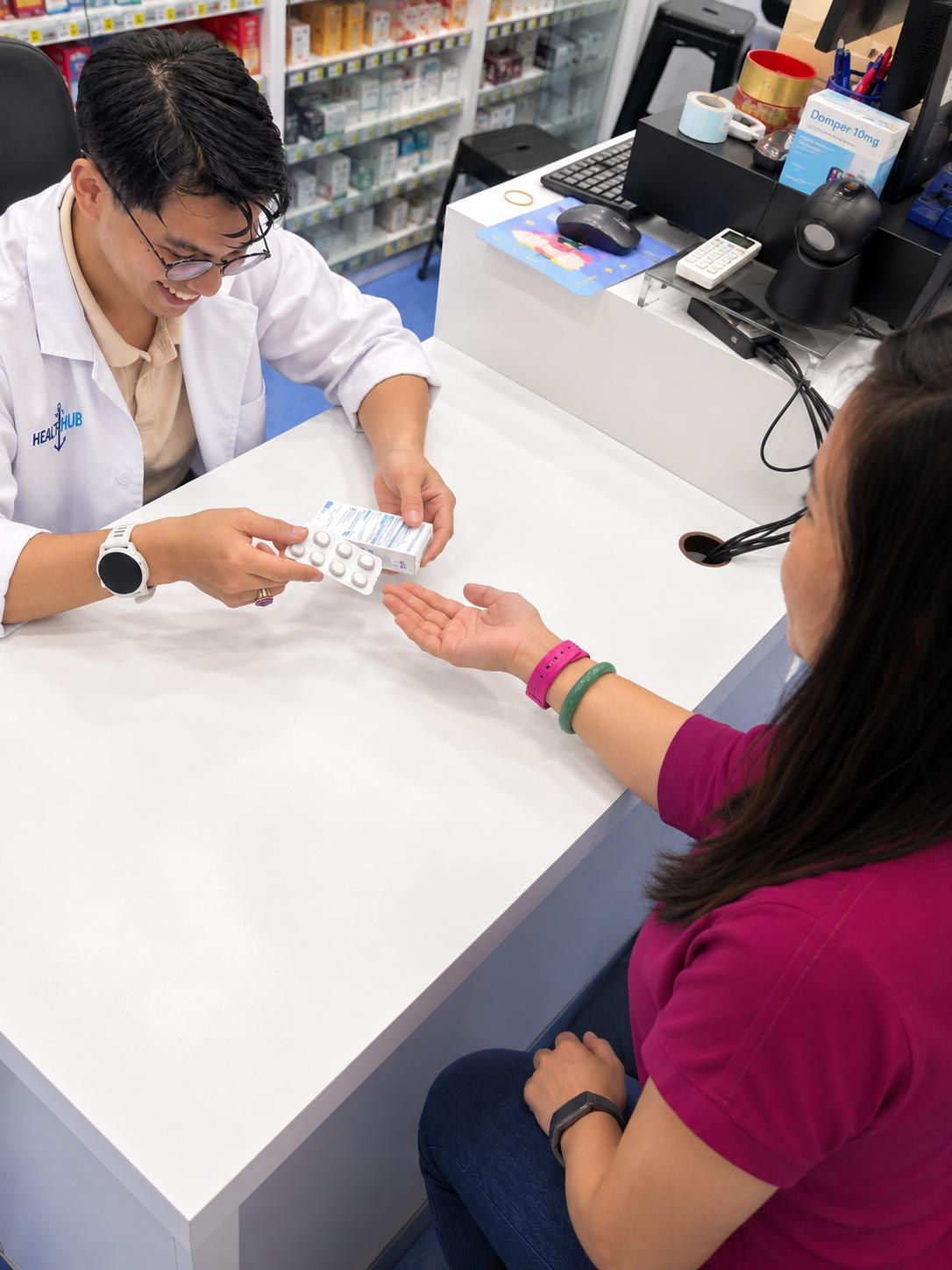 A HealthHub pharmacist handing medicine to a customer